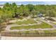Aerial view of a pump track with a blue picnic shelter, surrounded by green space within a fenced community park at 18144 Frame Bnd, Land O Lakes, FL 34638