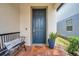 Inviting home entrance with a stylish blue door, brick flooring, and a cozy bench and plants at 18144 Frame Bnd, Land O Lakes, FL 34638