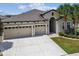 A front exterior view of the property, with a well-manicured lawn and three-car garage at 21837 Briske Morning Ave, Land O Lakes, FL 34637