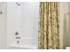 Shower with a white tub and white tiling and a neutral, floral shower curtain at 21837 Briske Morning Ave, Land O Lakes, FL 34637