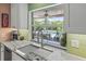 Bright kitchen boasts marble countertops, green tile backsplash, and a view to the pool area from a large picture window at 2581 61St S Ave, St Petersburg, FL 33712