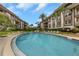 Community swimming pool surrounded by lounge chairs, lovely landscaping, and complex buildings at 3035 Countryside Blvd # 16B, Clearwater, FL 33761