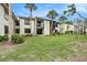 Exterior view of a two-story home with a lawn and mature trees at 326 Moorings Cove Dr # 2B, Tarpon Springs, FL 34689