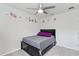 A cozy bedroom featuring a modern ceiling fan, floral wall decor, and a stylish bed at 39024 Harlow Rose Dr, Zephyrhills, FL 33540
