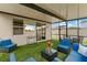 A screened-in patio with outdoor seating, artificial grass floor, and a mounted television at 39024 Harlow Rose Dr, Zephyrhills, FL 33540
