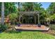 Backyard with wooden pergola and patio area, surrounded by a verdant, tropical landscape at 4096 38Th S St, St Petersburg, FL 33711