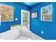 A blue home office featuring natural light from two windows and a glass paneled door complemented by a comfy white sofa at 4096 38Th S St, St Petersburg, FL 33711
