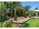 Lush backyard featuring a cozy pergola adorned with tropical plants and decorative pots, perfect for outdoor relaxation at 4096 38Th S St, St Petersburg, FL 33711