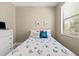 Guest bedroom with neutral walls featuring a comfortable bed, white dresser, and window with bright natural light at 4103 Via Piedra Cir # 10-101, Sarasota, FL 34233