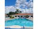 Large community pool with blue lounge chairs, palm trees, and a glimpse of the building behind it at 4470 Mainlands W Blvd, Pinellas Park, FL 33782
