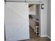 Kitchen adjacent to a sliding white barn door boasts bright white cabinets, stainless appliances, and a bar stool at 4470 Mainlands W Blvd, Pinellas Park, FL 33782