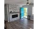Living room showcasing modern fireplace, ceiling fan, tile accent wall, and a blue front door at 4470 Mainlands W Blvd, Pinellas Park, FL 33782