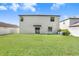 A spacious backyard featuring a lush lawn and a charming egg chair next to sliding glass doors at 4918 Wild Senna Blvd, Tampa, FL 33619