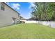 The spacious backyard has green grass and is enclosed by a white fence, with part of house on left at 4918 Wild Senna Blvd, Tampa, FL 33619