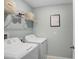 Bright laundry room with white washer and dryer, wire shelving, and laundry decor at 4918 Wild Senna Blvd, Tampa, FL 33619