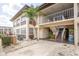 Inviting two-story condo building with a covered entrance, stairs, palm tree, and patio chairs for relaxing outdoors at 5111 Amulet Dr # 208, New Port Richey, FL 34652