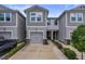 Gray townhome featuring a gray garage door, well-maintained landscaping, and a concrete driveway at 5813 Grand Sonata Ave, Lutz, FL 33558