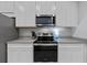Modern kitchen featuring stainless steel appliances, gray countertops, and white cabinets at 5813 Grand Sonata Ave, Lutz, FL 33558