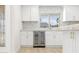 Kitchen wet bar featuring a wine cooler, white cabinets, and herringbone backsplash at 6400 Mockingbird S Way, St Petersburg, FL 33707