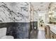 Modern bathroom with black and white marble walls, hexagon tile floor, standing plant, and stylish gold fixtures at 6401 N Central Ave, Tampa, FL 33604