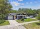 Exterior home view with lush front yard, cozy front porch, and attached garage in a quiet neighborhood at 6401 N Central Ave, Tampa, FL 33604