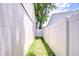 Narrow side yard featuring a white privacy fence and a gate leading to a tree-filled area at 6720 Gilda Dr, Tampa, FL 33625