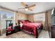 Cozy bedroom with a ceiling fan, windows, and a comfortable bed with red comforter at 7631 Ironbark Dr, Port Richey, FL 34668