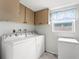 Bright laundry area features overhead cabinets, washer, dryer, freezer and window at 7631 Ironbark Dr, Port Richey, FL 34668