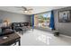A comfortable living room with a large window, a black leather sofa set, tile floors, and ceiling fan at 7631 Ironbark Dr, Port Richey, FL 34668