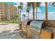 Outdoor kitchen area with stainless steel grills for residents, with ocean views and palm trees at 880 Mandalay Ave # C513, Clearwater Beach, FL 33767