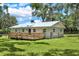 View of the back of the home, displaying a wooden deck, backyard and metal roof at 9448 Mcintyre Rd, Brooksville, FL 34601