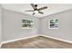 Bright bedroom with hardwood floors, a ceiling fan, and two windows providing natural light at 9448 Mcintyre Rd, Brooksville, FL 34601