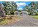 Exterior of house showcasing gravel driveway and grassy yard with several large trees at 9448 Mcintyre Rd, Brooksville, FL 34601