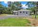 Exterior of home with grassy yard and gravel driveway in a tree-filled lot at 9448 Mcintyre Rd, Brooksville, FL 34601