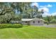 Side view of home with a grass yard and mature trees behind a fenced in yard at 9448 Mcintyre Rd, Brooksville, FL 34601