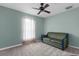 Bedroom with neutral carpeting, a ceiling fan, and a green loveseat by the window at 10457 Cranston St, Spring Hill, FL 34608