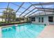 A screened pool with clear blue water reflecting the enclosure and palm tree at 10457 Cranston St, Spring Hill, FL 34608
