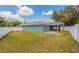 Large backyard with a green lawn, screened-in porch, and a white fence at 11448 Bay Gardens Loop, Riverview, FL 33569