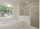 Bright bathroom featuring a large window, soaking tub, and glass enclosed shower at 1156 Ridgegrove W Dr, Palm Harbor, FL 34683