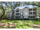 Charming condo building with screened-in porches surrounded by lush green lawns and mature trees at 1201 High Hammock Dr # 302, Tampa, FL 33619