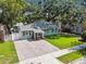 Charming single-story home showcasing manicured lawn, brick driveway, and mature trees at 1208 E Crenshaw St, Tampa, FL 33604