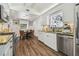 Open kitchen with white cabinets, granite countertops, and stainless steel appliances, adjacent to dining area at 1208 E Crenshaw St, Tampa, FL 33604