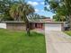 Charming single-story home featuring stone accents, a two-car garage, and a lush green lawn with a mature palm tree at 1309 Eastfield Dr, Clearwater, FL 33764