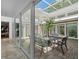 Relaxing sunroom featuring brick floors, a glass roof, and a wrought iron patio set at 1309 Eastfield Dr, Clearwater, FL 33764