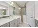 Bathroom features gray cabinets, white double sinks, large mirror, and glass shower with gray tile at 13524 Circa Crossing Dr, Lithia, FL 33547