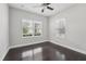 Neutral bedroom with dark wood floors, two windows with views, and a ceiling fan at 13524 Circa Crossing Dr, Lithia, FL 33547