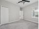 Carpeted bedroom featuring a ceiling fan, a window, and closet space for comfort and convenience at 13524 Circa Crossing Dr, Lithia, FL 33547