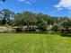 Backyard view with lush green grass, a tranquil pond and mature trees at 140 Nina Way, Oldsmar, FL 34677