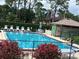 Community pool with mature trees, lounge chairs, tables and umbrellas create a relaxing oasis at 140 Nina Way, Oldsmar, FL 34677