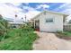 Exterior shot with a cracked driveway and an entryway with mature plants at 1580 Arizona Ave Ne, St Petersburg, FL 33703